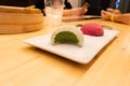 Green tea biten and red raspberry big mochi on a plate on a wooden table in an asian restaurant or chinese dumplings. bar. Green