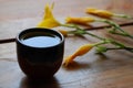 Green tea bowl on a dark brown wooden background with beautiful yellow lilies