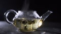 Green tea is brewed in a glass teapot on a black background.