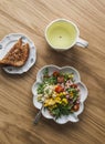 Green tea, crispy wholegrain toast and salad with canned tuna, boiled egg, arugula, cherry tomatoes and corn on a wooden