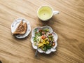 Green tea, crispy wholegrain toast and salad with canned tuna, boiled egg, arugula, cherry tomatoes and corn on a wooden