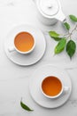 Green tea in cups with leaves and teapot on white marble table, flat lay Royalty Free Stock Photo