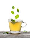 Green tea with falling mint leaves in glass cup isolated on white