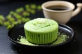 a green tea-flavored cupcake on a black ceramic plate