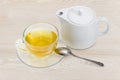 Green tea in glass cup on saucer, tea spoon, teapot Royalty Free Stock Photo