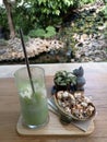 Green tea is in a glass and popcorn in a brown plate placed on the table for a blurred background.