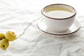 Green tea with japanese quince on white linen textile, minimalist composition with herbal tea in white cup with fruit branch