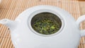 Green tea leaves steeping in a beautiful white porcelaine teapot