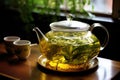green tea leaves steeping in a clear glass teapot