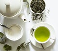 Green tea - tea leaves, teacup, teapot, sugar bowl on a white background, top view, close-up