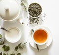 Green tea - tea leaves, teacup, teapot, sugar bowl on a white background, top view
