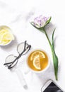 Green tea with lemon, tulip flower, headphones, smartphone - free relax time still life on a white background, top view Royalty Free Stock Photo