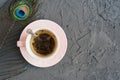 Green tea in a pink cup and decorative peacock feather