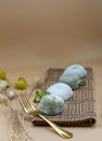 Green tea and Red bean daifuku serve with brass fork on bamboo placemat with orange background