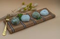 Green tea and Red bean daifuku serve with brass fork on bamboo placemat with orange background