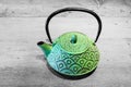 Green teapot on grey wooden background