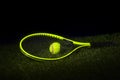 Green tennis racket with tennis balls in green color on grass with black background and copy space Royalty Free Stock Photo