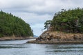 Green tent on an island beach in the San Juan Islands, rocky shores, tree covered islands, Salish Sea, cloud cover, Pacific Northw