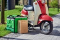 Green Thermal Backpack And Paper Bag Standing Near Motor Scooter On The Sunny City Street. Food Delivery Services