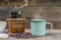 A Green tin cup of hot coffee with coffee grinder and coffee bean on the wooden table Royalty Free Stock Photo