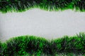 Green tinsel garlands on silver glittery background.
