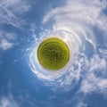 Green tiny planet in blue sky with sun and beautiful clouds. Transformation of spherical panorama 360 degrees. Spherical abstract