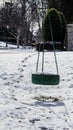 Green tire swing in neighborhood yard in snow with shadows and footprints leading from neighbors yard to swing Royalty Free Stock Photo