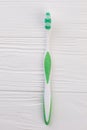 Green tooth brush on white wooden background.