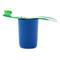 Green toothbrush with paste lying on blue plastic cup isolated over white background Royalty Free Stock Photo