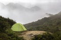 Green tourist tent on a background of mountain peaks in the fog. Royalty Free Stock Photo