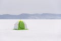 Green tourist tent in front of the icy mountain.