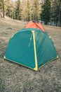 Green tourist tent on yellow dry grass on sunny day. Camping in pine forest for outdoor recreation Royalty Free Stock Photo