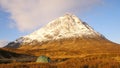 Green touristic tent on meadow at river below snowy cone of mountain Stob Dearg 1021 metres high. Hike in Higland in Scotland