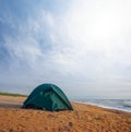 Green touristic tent stay on the sandy stormy sea beach Royalty Free Stock Photo