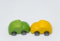 Green toy car accident crashed yellow toy car with white background and selective focus