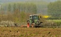 Green tractor in field cultivating soil