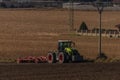 Green tractor plough brown autumn field near Steti town