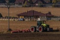 Green tractor plough brown autumn field near Steti town