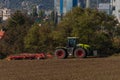 Green tractor plough brown autumn field near Steti town