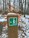 A GREEN TRAIL MARKER GUIDES HIKERS ALONG A SNOWY TRAIL IN A PUBLIC PARK