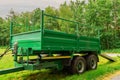 Green trailer in a field with ramp down by a forest. Concept heavy machinery delivery