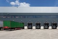 Green trailer in front of a loading door at a warehouse under a blue sky