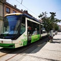 A green tram parked at a bus stop