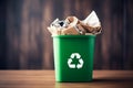 Green trash bin filled with waste paper ready for recycling isolated on wooden background with copy spcae. Waste paper Royalty Free Stock Photo