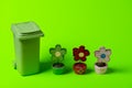 Green trash can with flowers on a green background Royalty Free Stock Photo