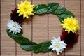 Green tree leaf with white, red, and yellow Chrysanthemum flower frame on bamboo mat Royalty Free Stock Photo