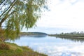 A green tree on the river bank. Reflection of trees and clouds on the water surface of the river. Autumn landscape Royalty Free Stock Photo