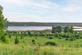 Green trees in the field and a blue lake in the distance