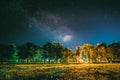 Green Trees Woods In Park Under Night Starry Sky. Night Landscape With Natural Real Glowing Milky Way Stars Over Meadow Royalty Free Stock Photo