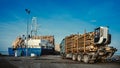 Green truck carrying pulpwood to the cargo ship in the port. Summer time. Close up. Copy space